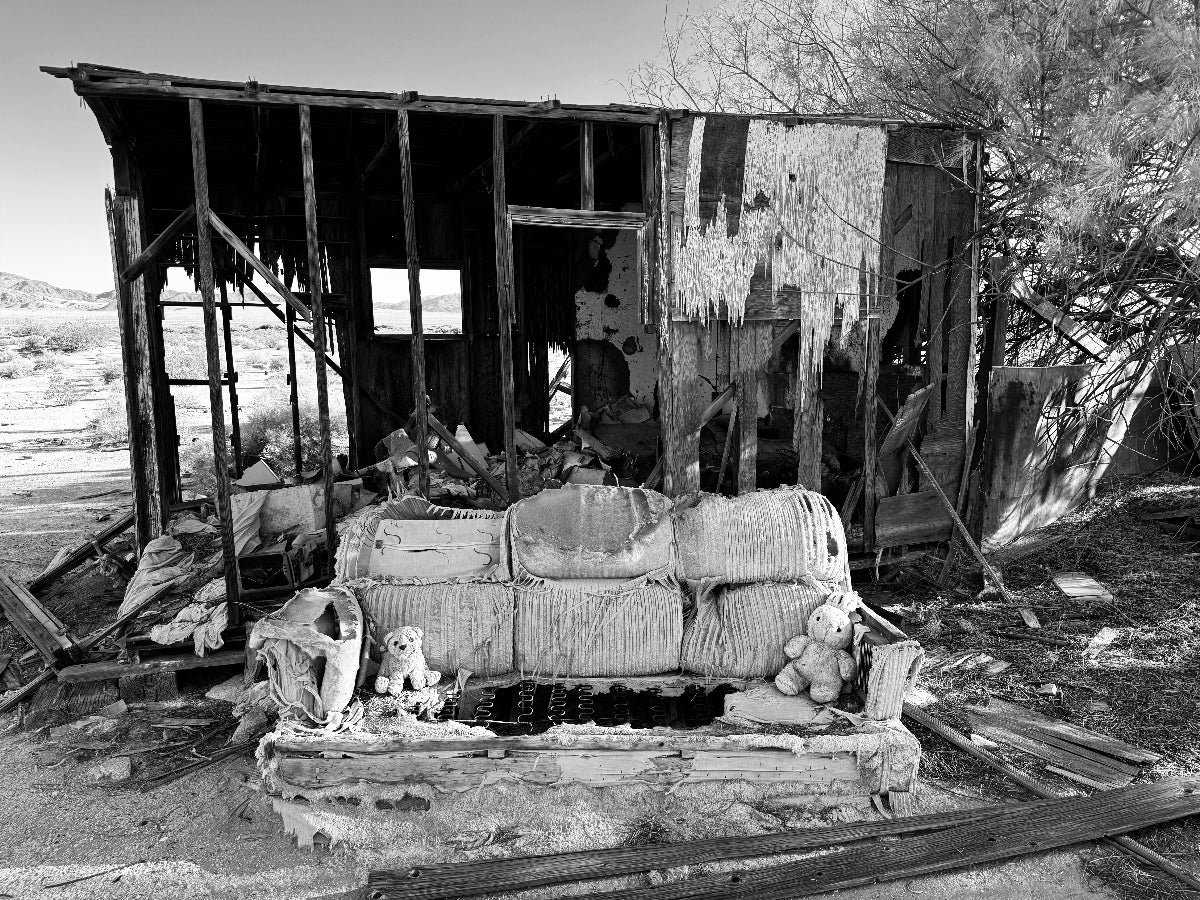 Rustic wooden cabin with scattered furniture and toys in a desert setting