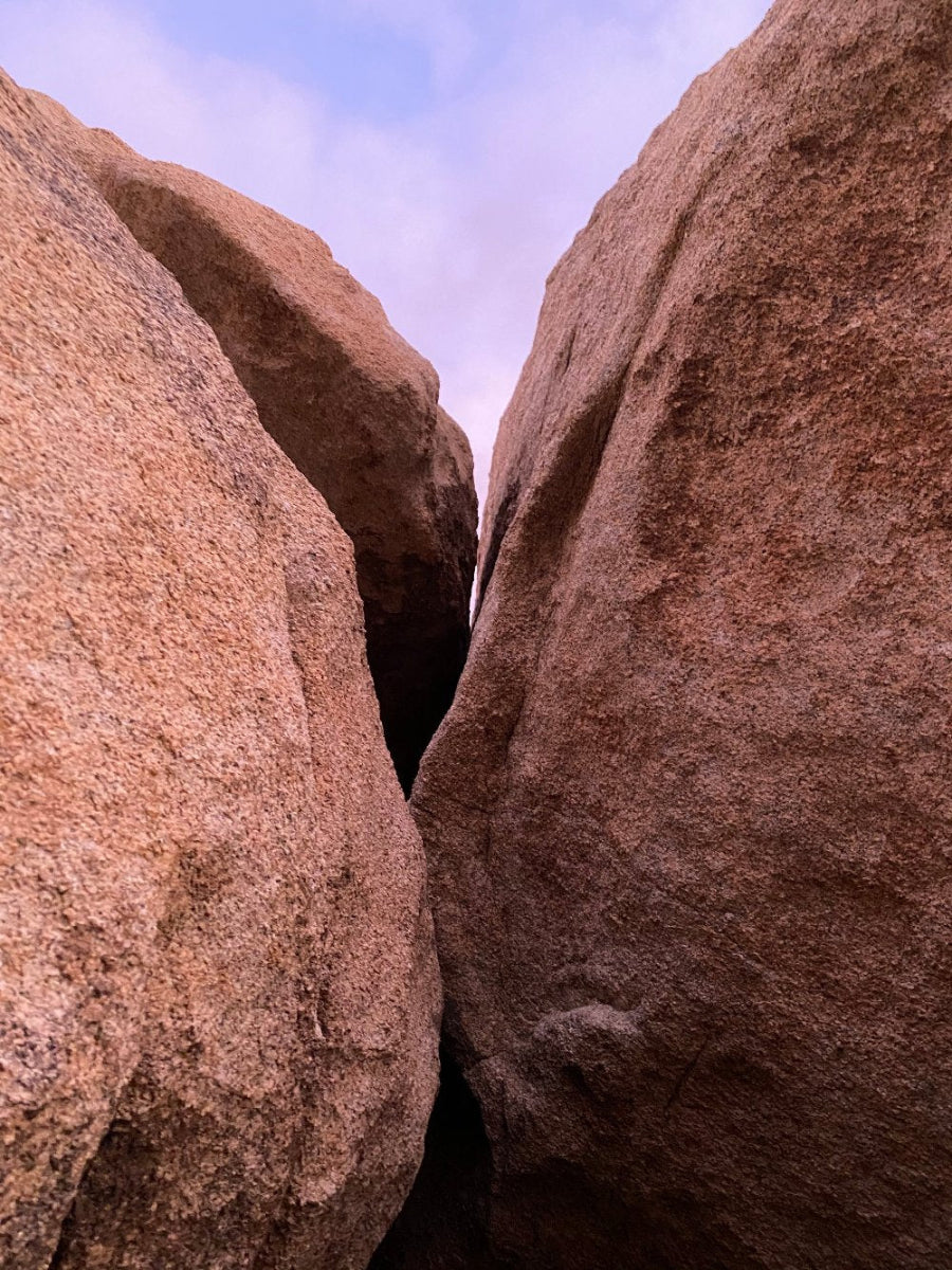 A photograph titled 'Boulders Kiss' showing two large boulders in an embracing and kissing posture in Joshua Tree National Park, California.