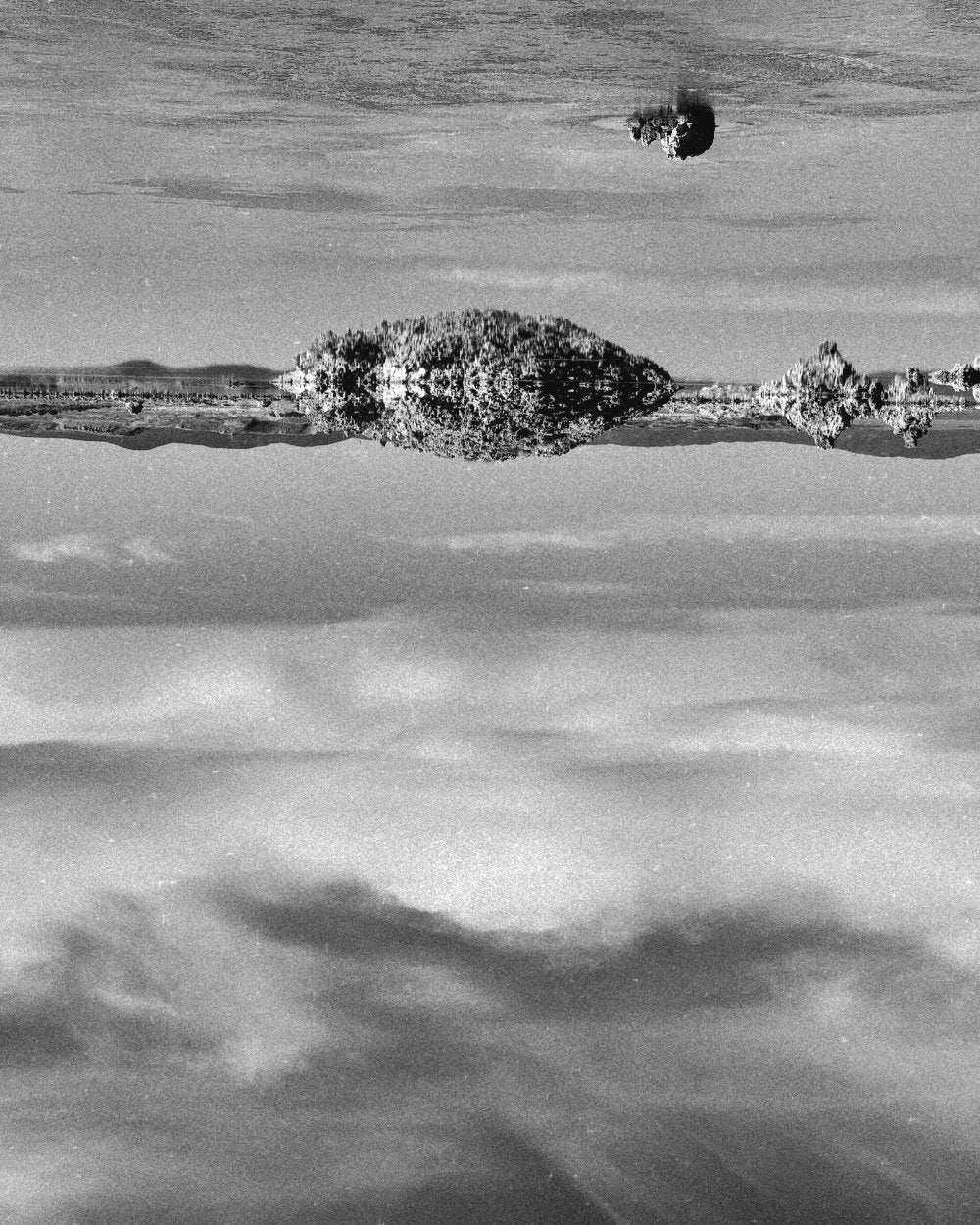 Black and white image of Mono Lake with a reflection of the sky and clouds, Mono County, California.