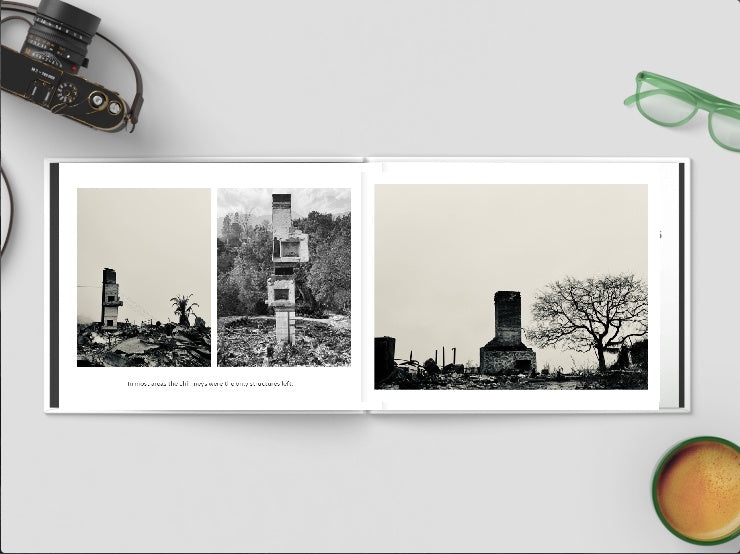 Photobook with black and white images of a tower and trees on a white surface with a camera and glasses.