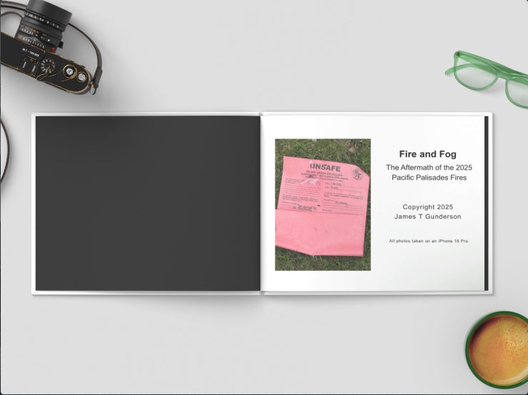 Book titled 'Fire and Fog' on a white surface with a camera and glasses in the background.