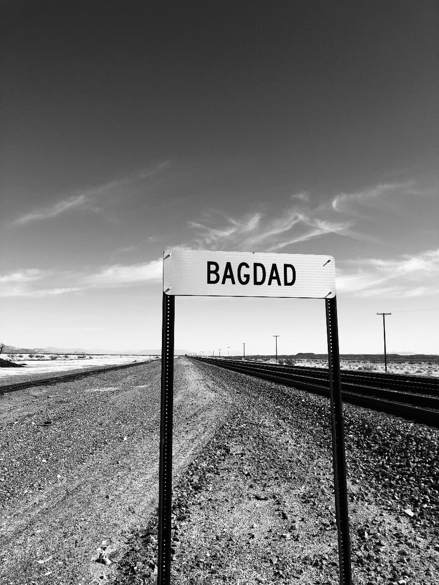 Black and white signpost with 'Bagdad' on a desert landscape