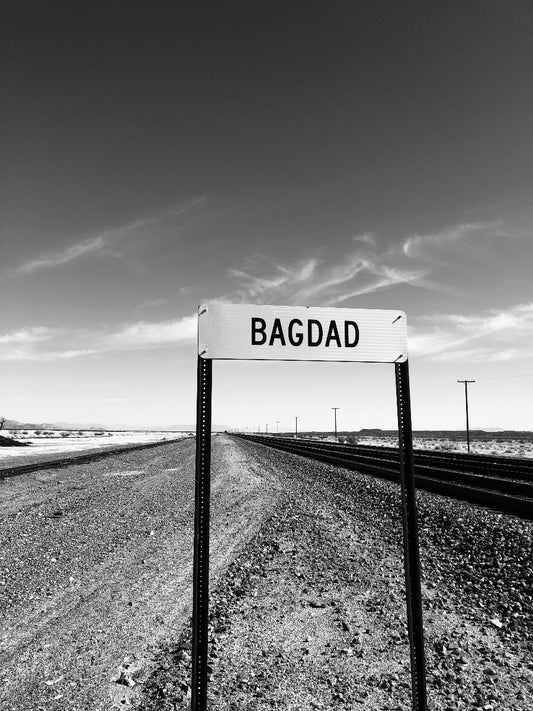 Black and white signpost with 'Bagdad' on a desert landscape