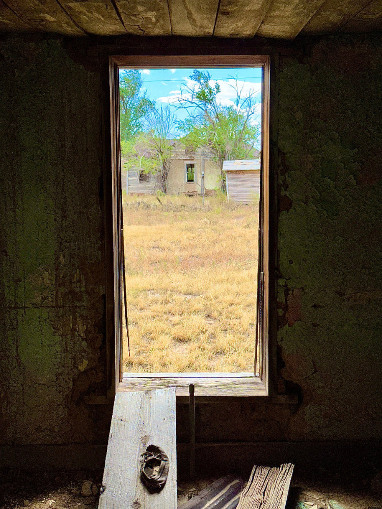 Fine art photography print of a broken window in an abandoned Encino, New Mexico building framing the desert landscape beyond — by James Gunderson