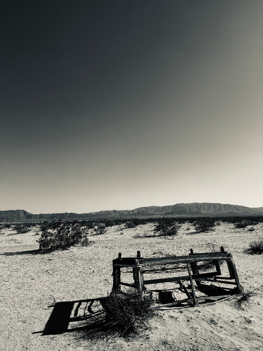 Worn wooden sofa in a desert landscape with mountains in the background