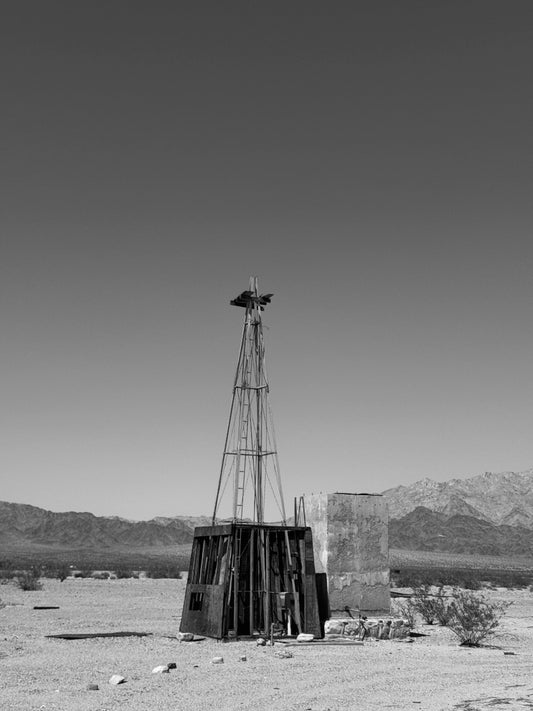 Vintage windmill in a desert landscape with mountains in the background
