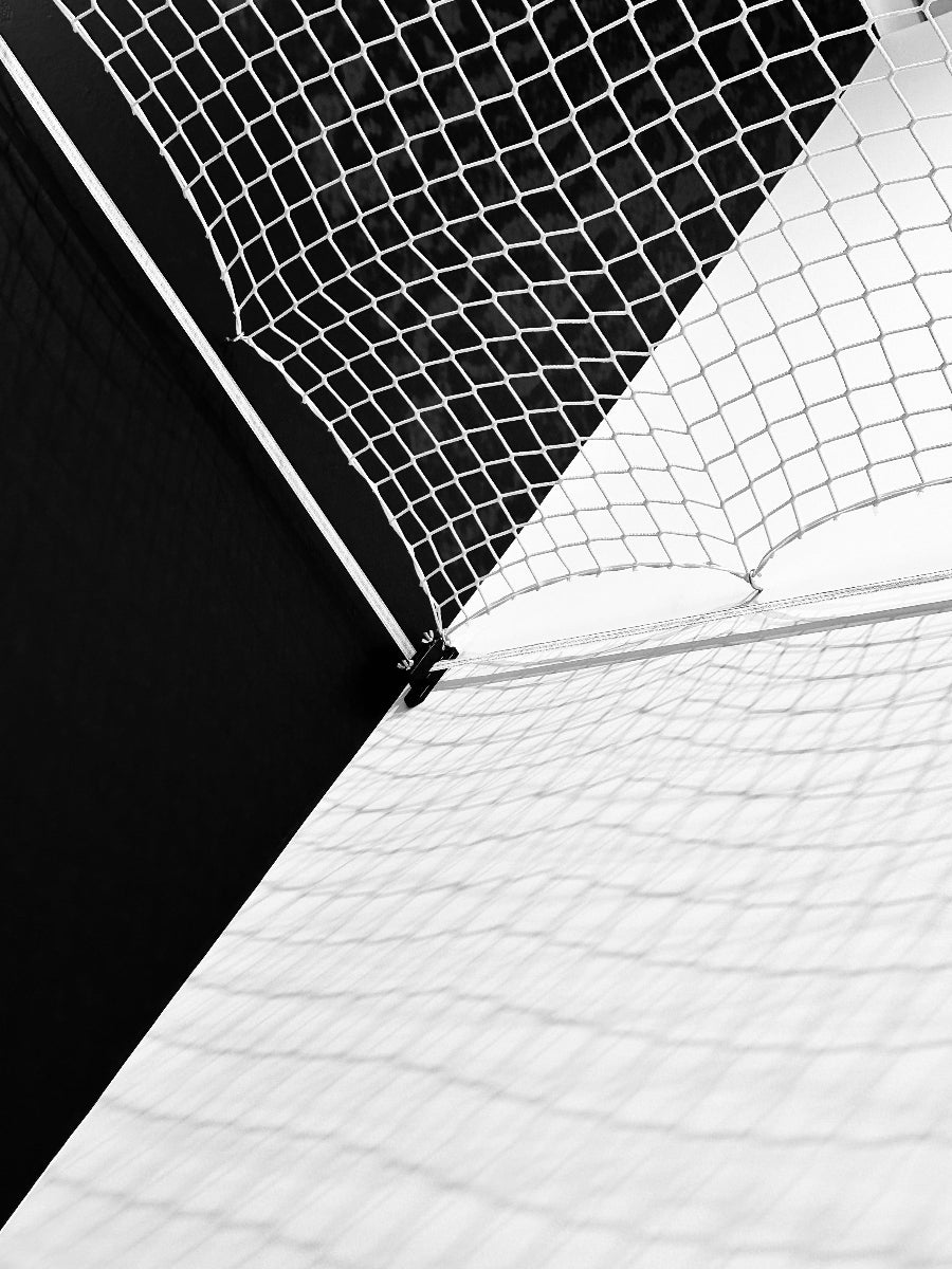 Close-up of a soccer goal with black netting on a white background